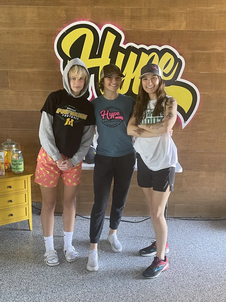 Three Hype crew members in front of the Hype sign