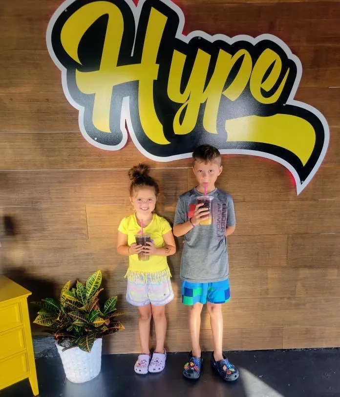 Two kids with their Hype drinks at the Hype sign