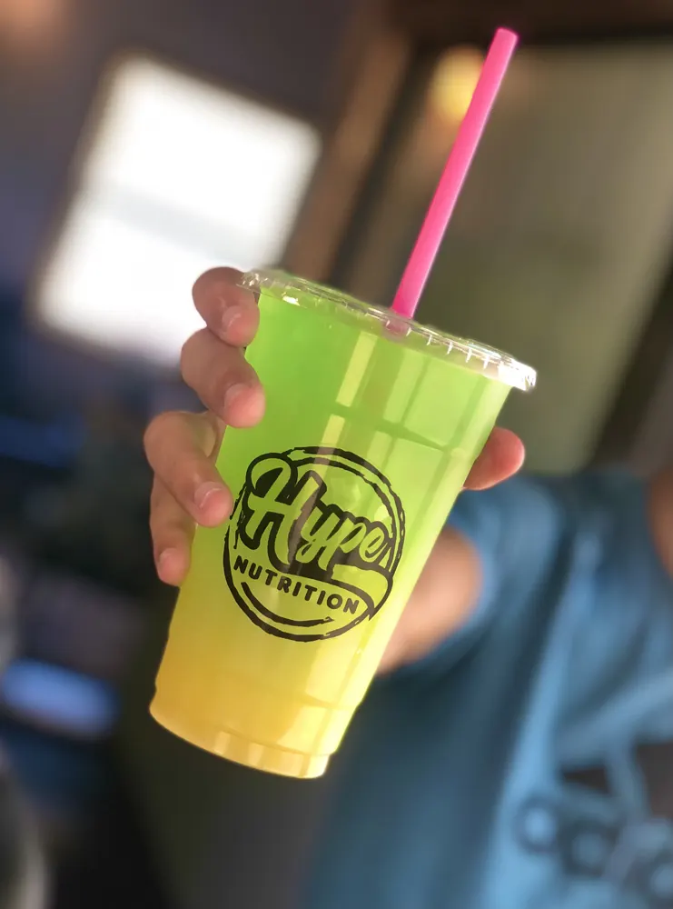 A green and yellow Hype drink held up