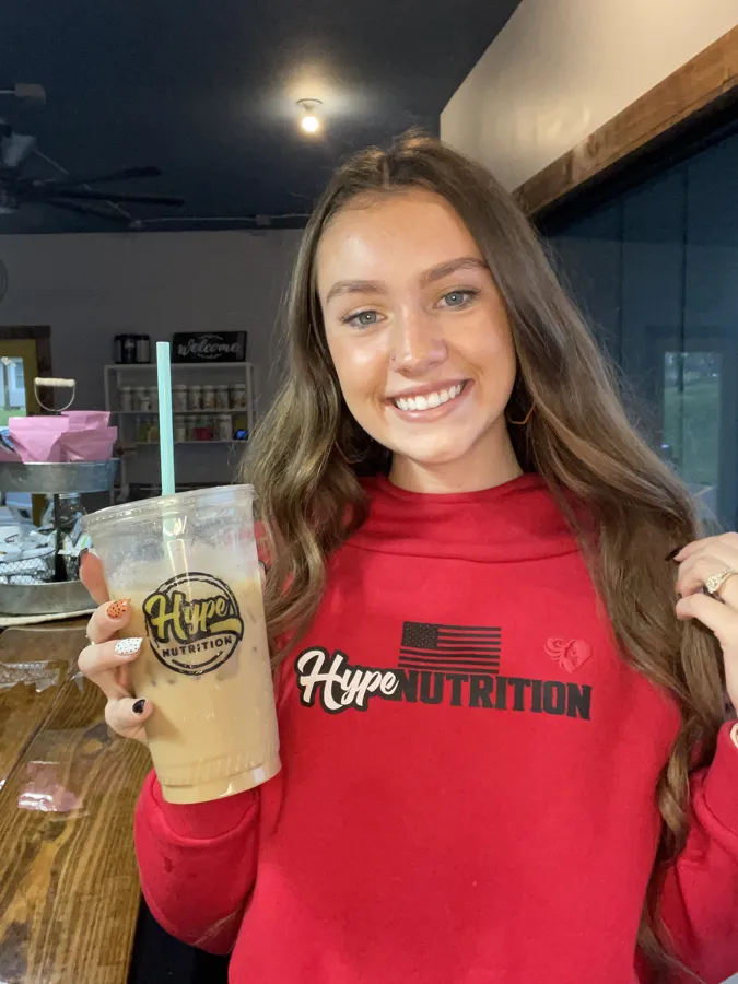 Smiling Hype customer in a red Hype hoodie holding her drink