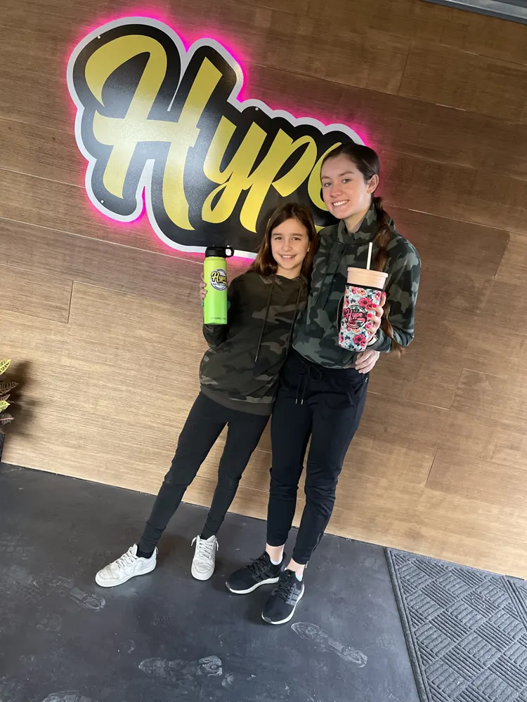 Two customers with their Hype drinks at the sign