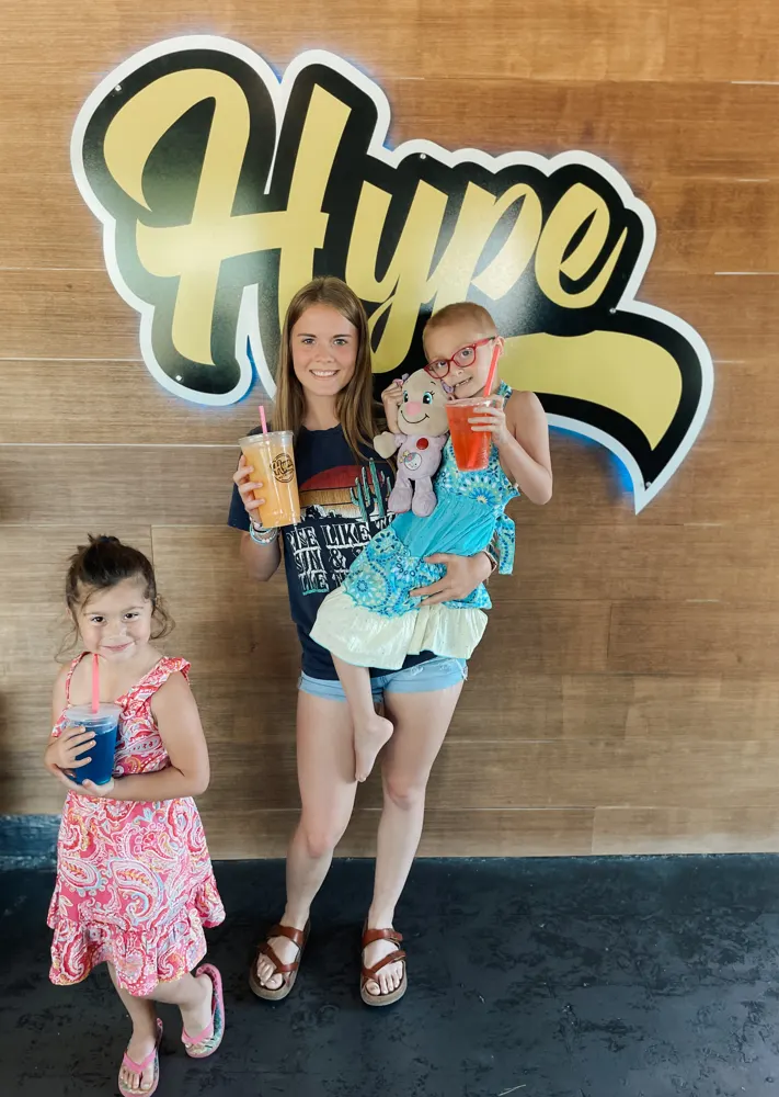 A mom and her girls with Hype drinks at the Hype sign
