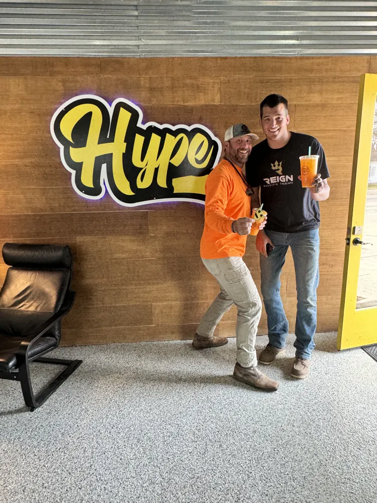 Two customers with their Hype drinks at the sign