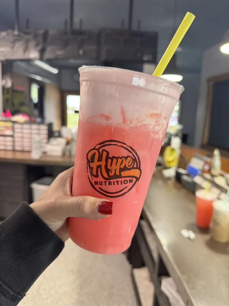 A pink Hype drink held up in the shop