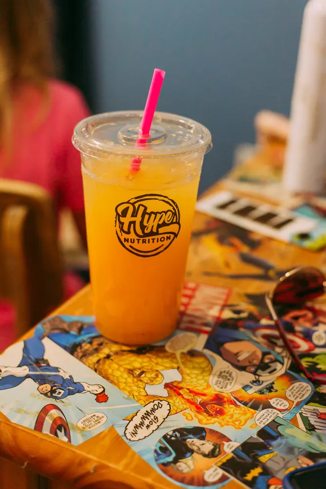 An orange Hype drink on a comic-book table