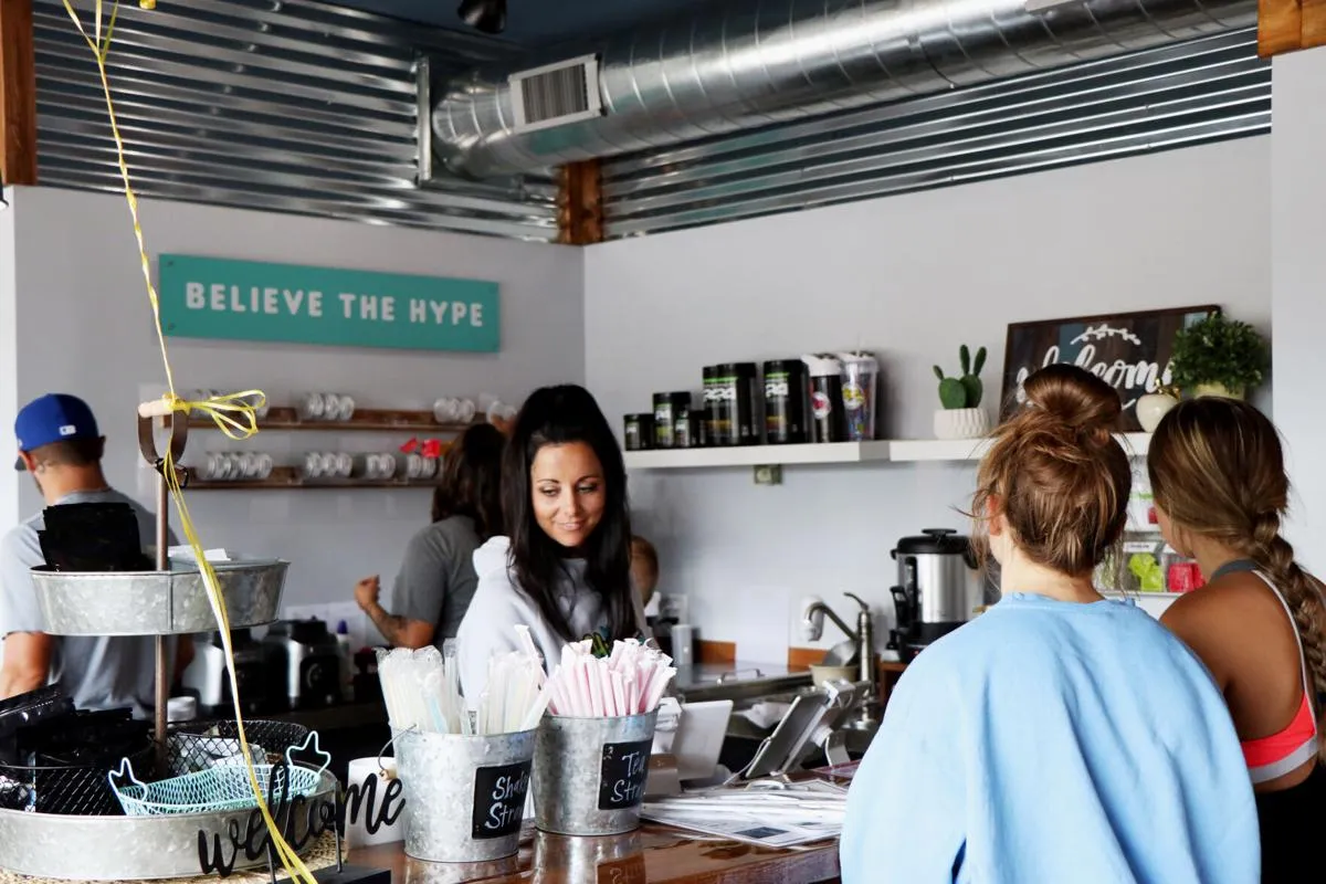 Reba making drinks behind the Hype counter under the Believe the Hype sign