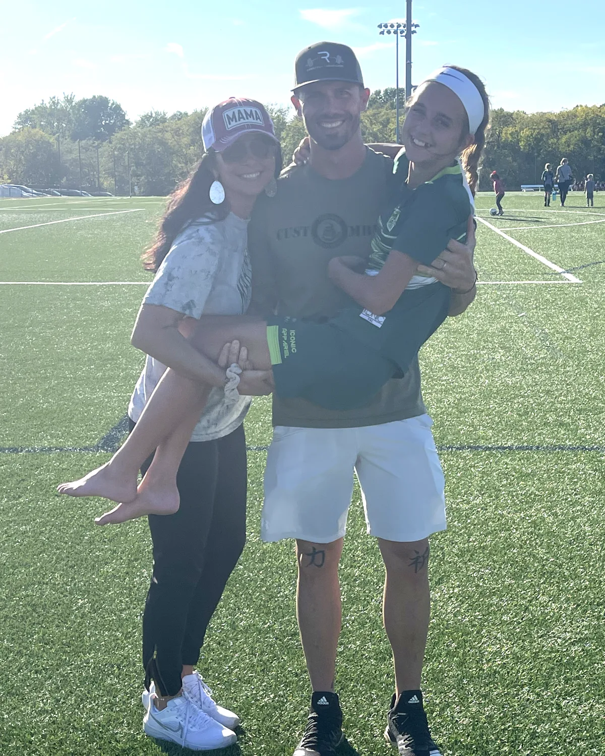 Reba and Jake holding their daughter on the soccer field