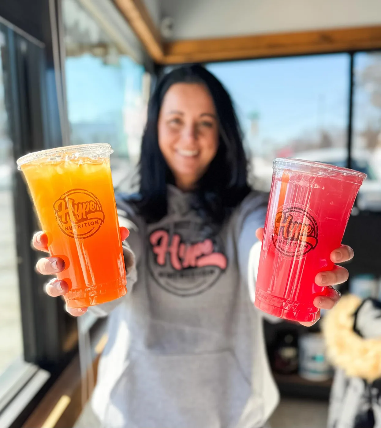 Reba holding out two Hype drinks by the shop window